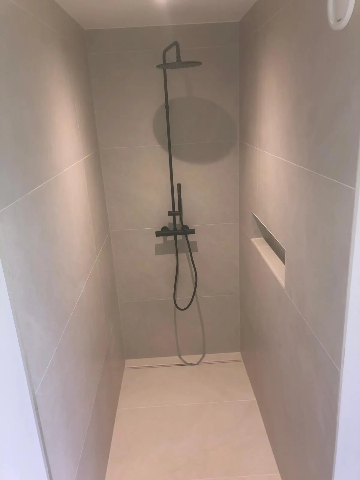 Bodengleiche Dusche mit Wandnische und schwarzer Armatur