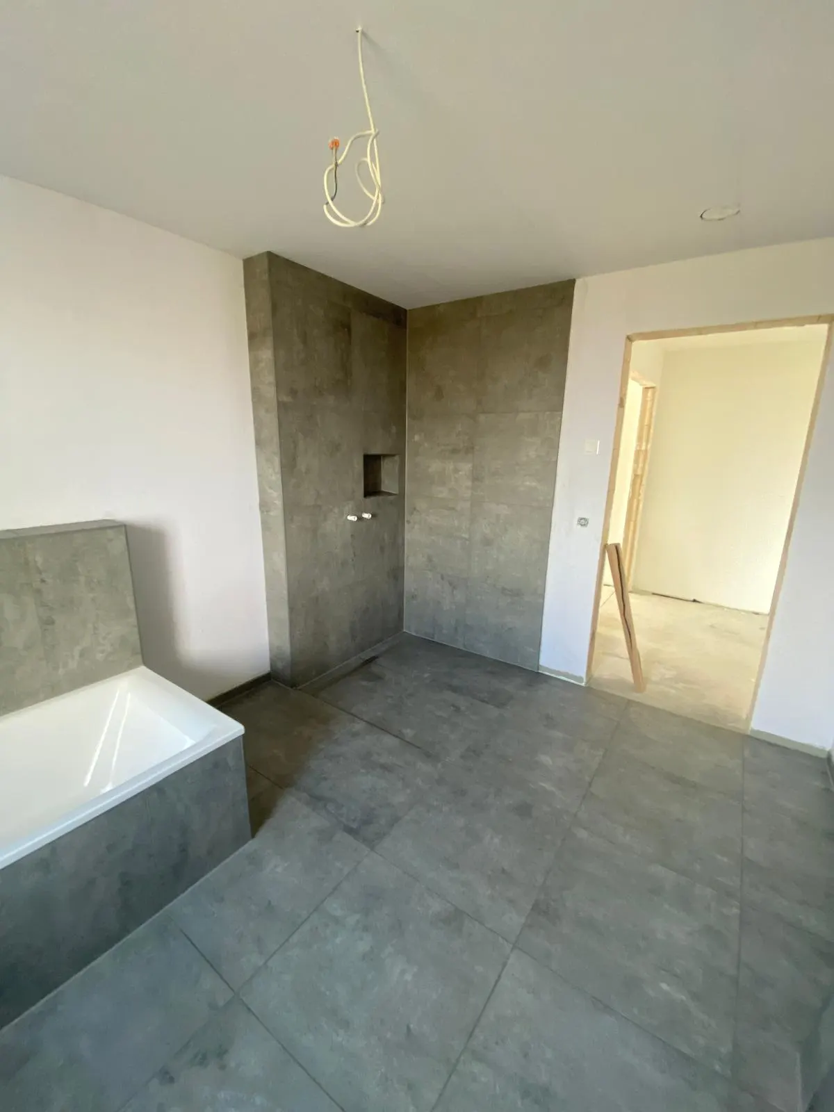 Bad mit großformatigen Wandplatten und offener Dusche