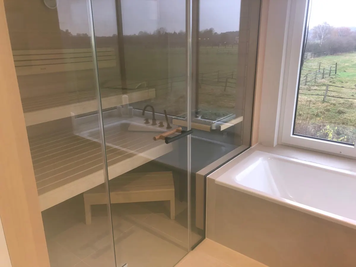 Badezimmer mit Glasdusche, Badewanne und Sitzbank