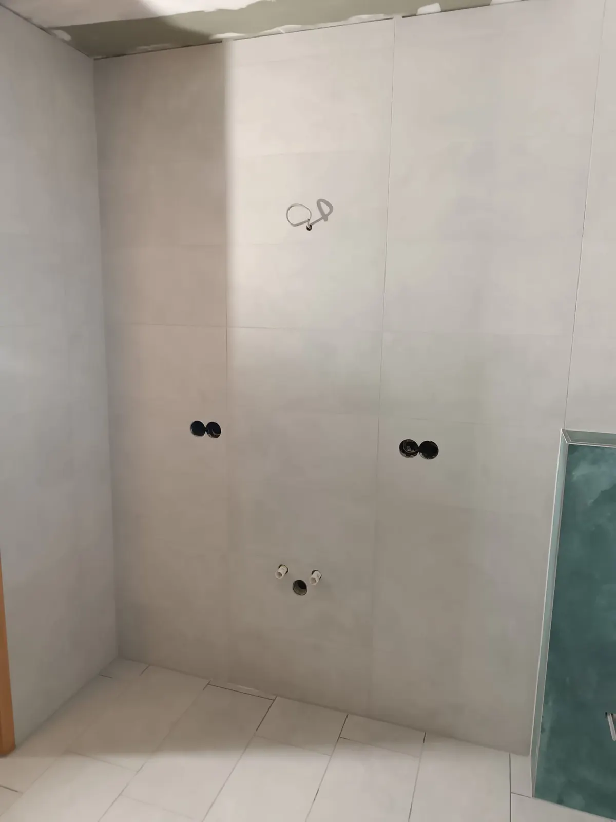 Bad im Rohbau mit verlegten Wandfliesen und offener Dusche