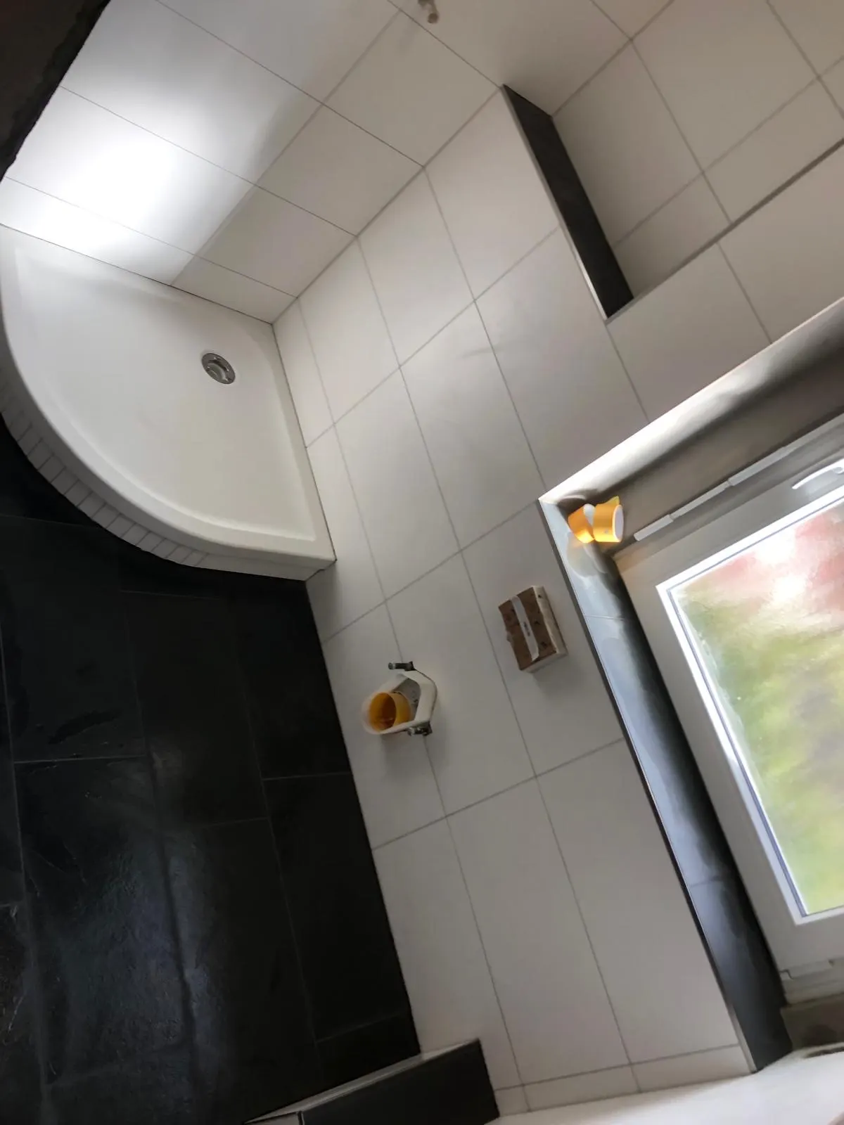 Bad mit Rundduschtasse und großformatigen Wandfliesen