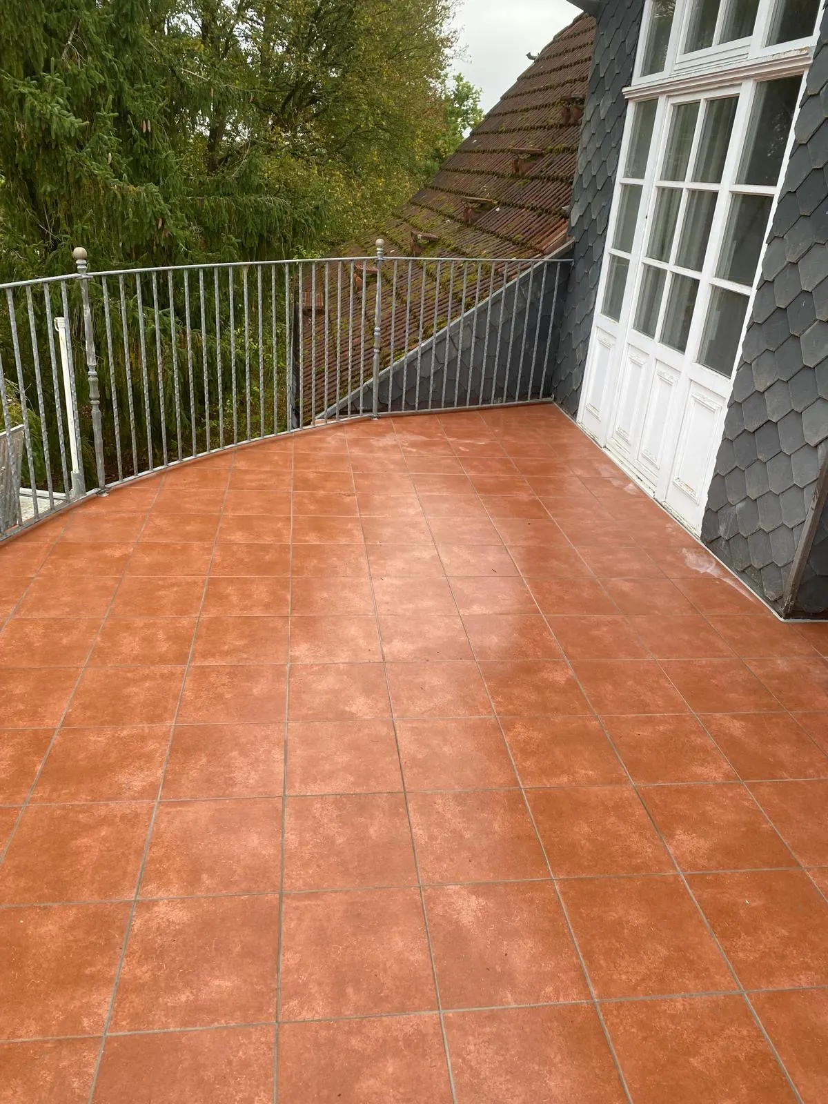 Terrasse mit rötlichen Bodenplatten und Geländer